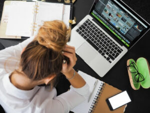 Woman sitting at her computer with her head in her hands