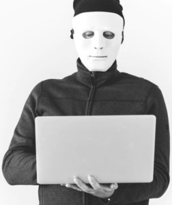 man in a mask holding a laptop