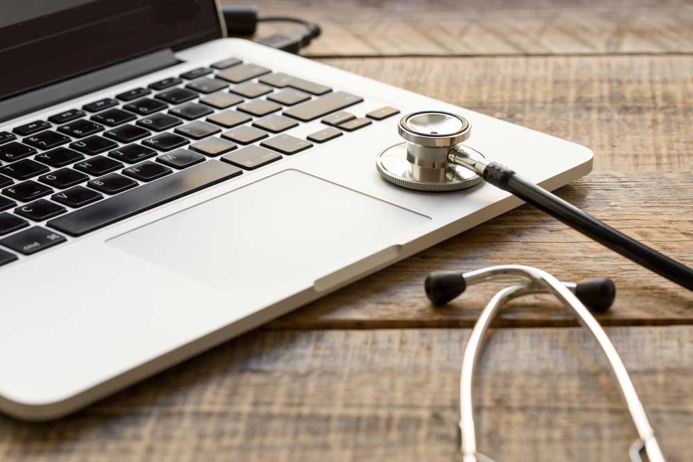 A laptop with a stethoscope sitting on top of it