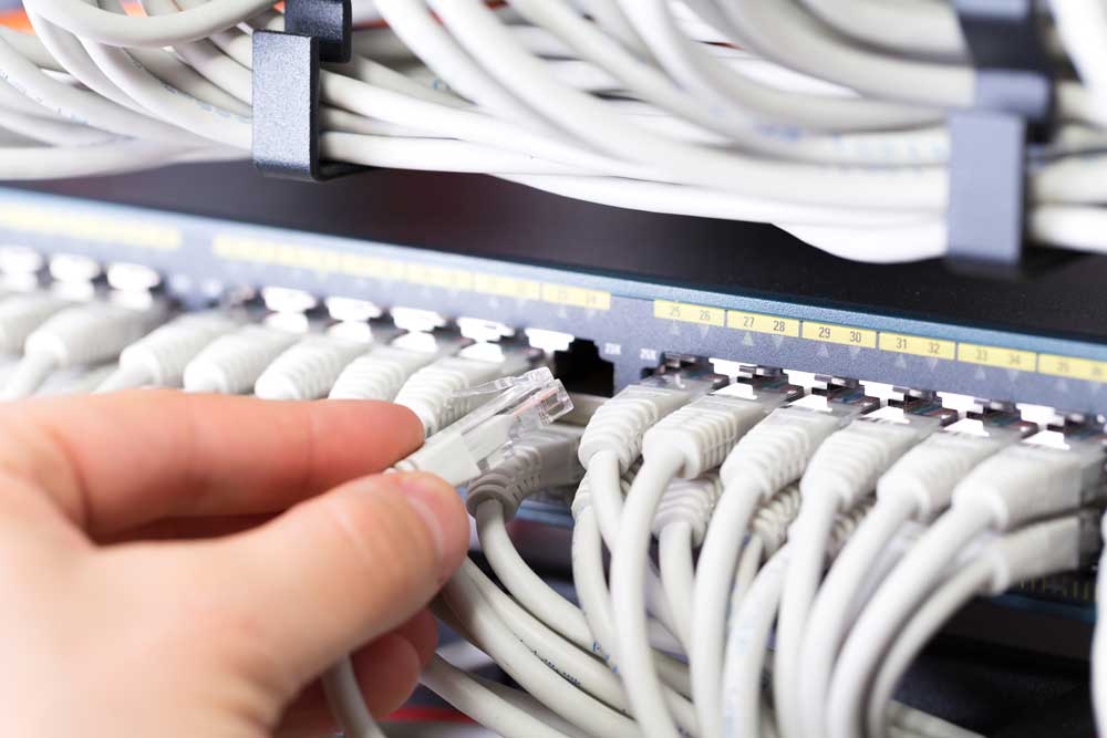 Managed IT Services consultant connects a network cable into switch