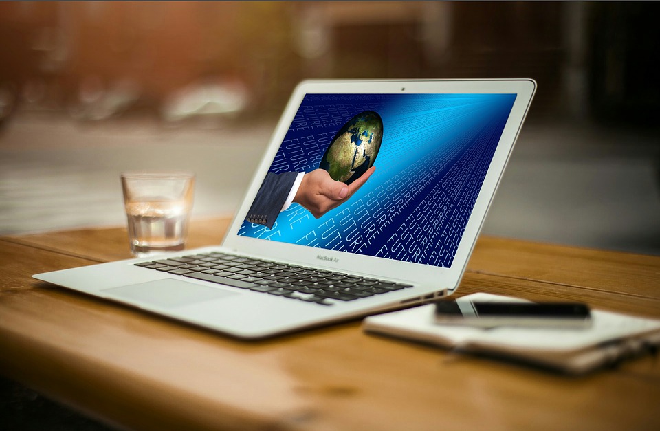 Laptop on a desk with a picture of a hand holding a globe